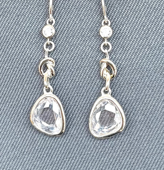 Silver earrings with teardrop-shaped clear gemstones on a gray textured background