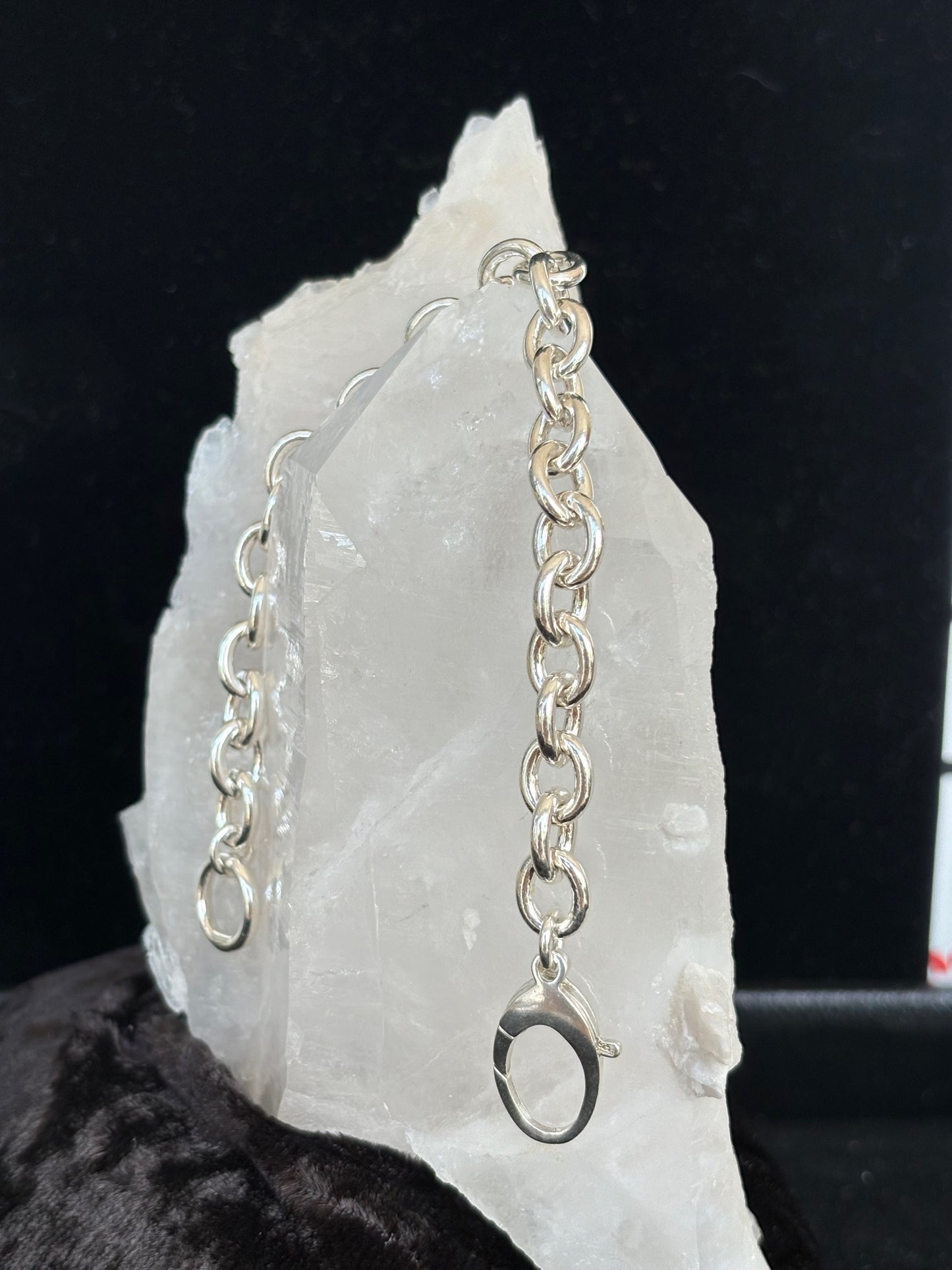 Sterling silver chain bracelet on a white stone surface with a dark background
