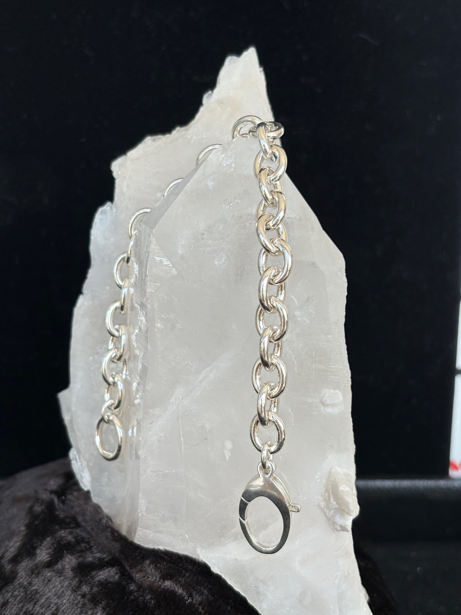 Sterling silver chain bracelet on a white stone surface with a dark background