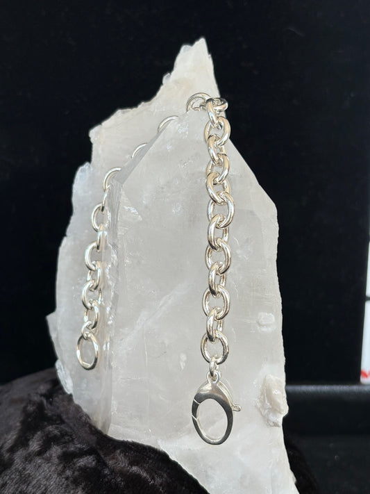 Sterling silver chain bracelet on a white stone surface with a dark background
