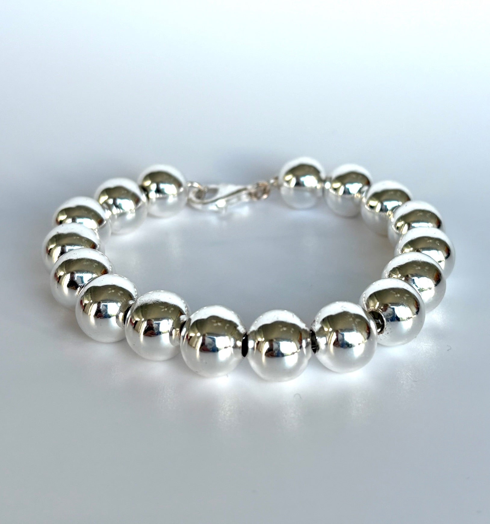 Stelring Silver beaded ball bracelet  on a light gray background. Jolie Esprit