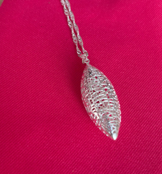 Silver leaf-shaped pendant on a chain against a pink background