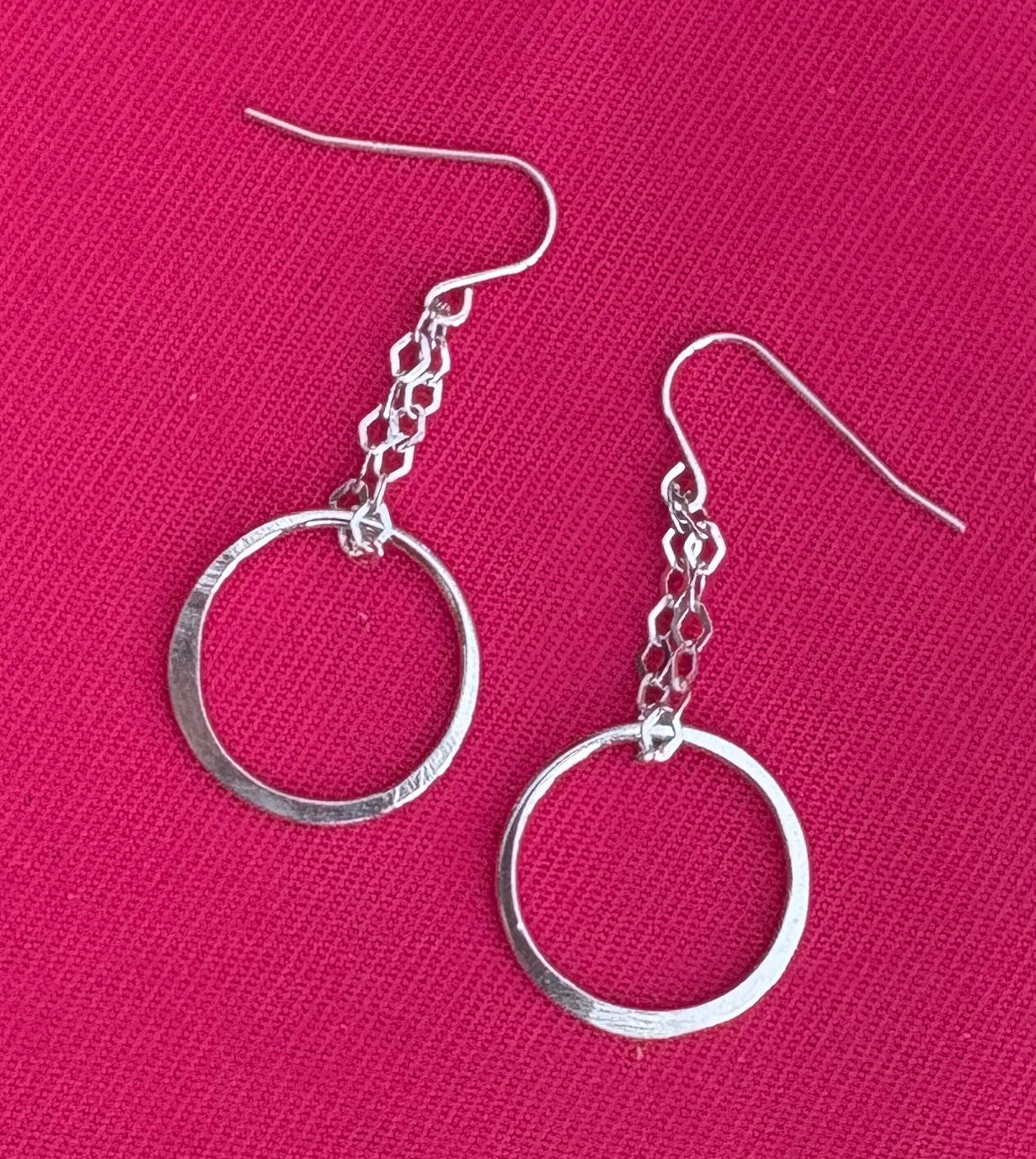 Silver hoop earrings on a pink background