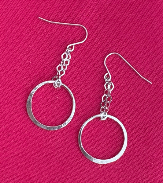 Silver hoop earrings on a pink background