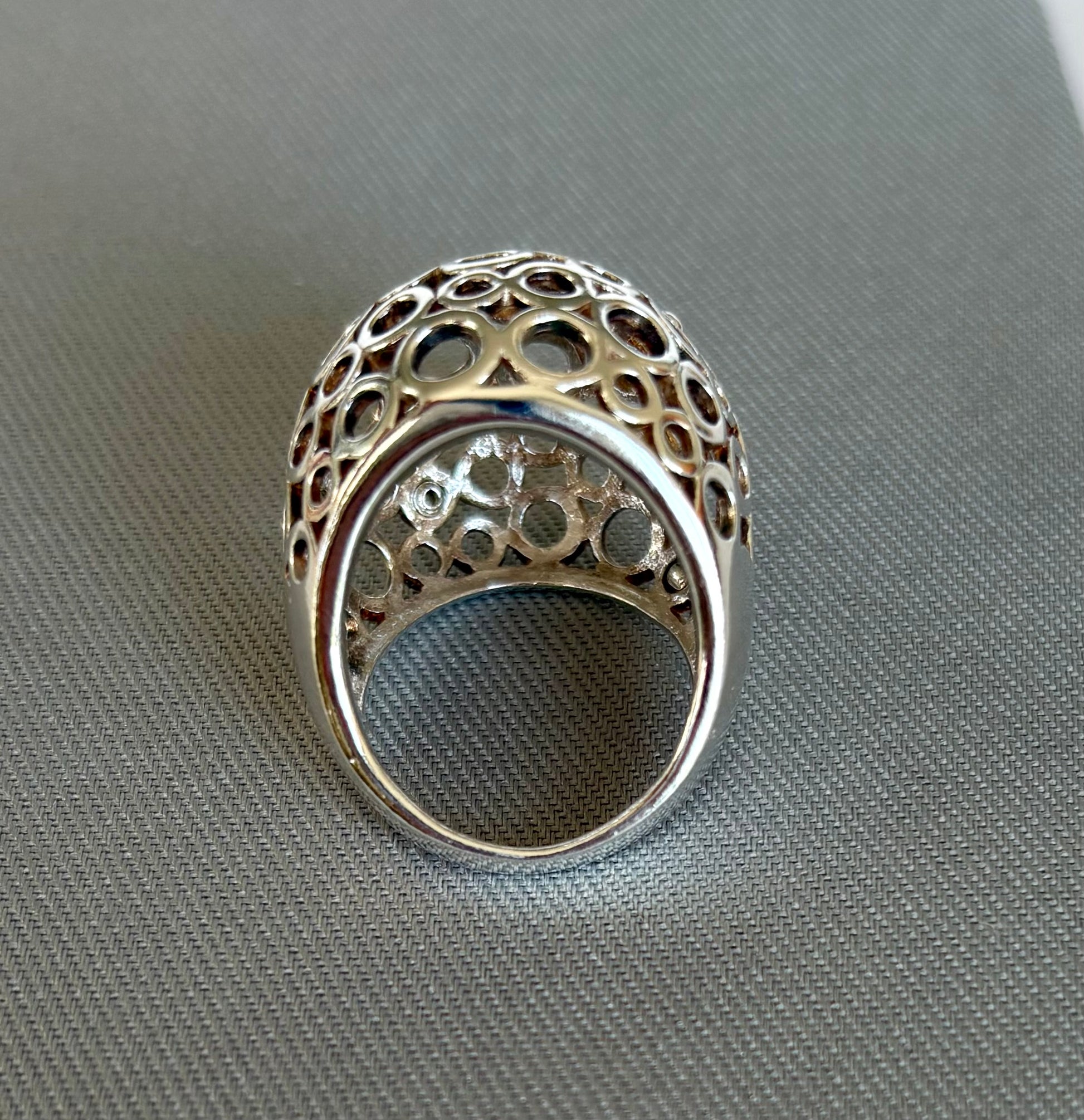 Silver ring with intricate design on a gray surface