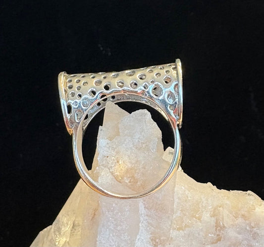 Silver ring with unique design on a crystal rock against a black background