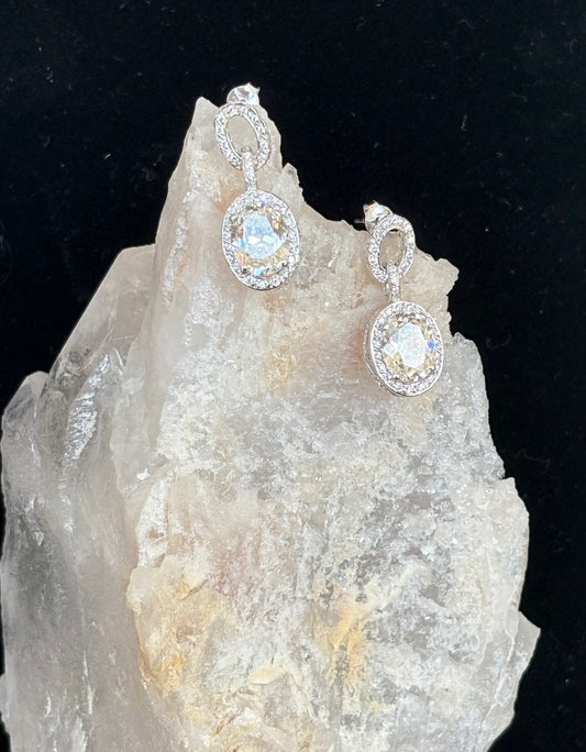 Silver earrings with gemstones on a crystal rock against a black background