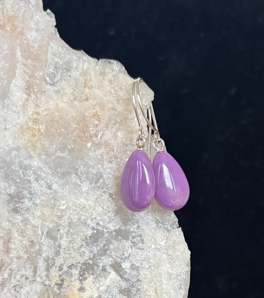 Purple teardrop earrings on a dark background with a textured surface