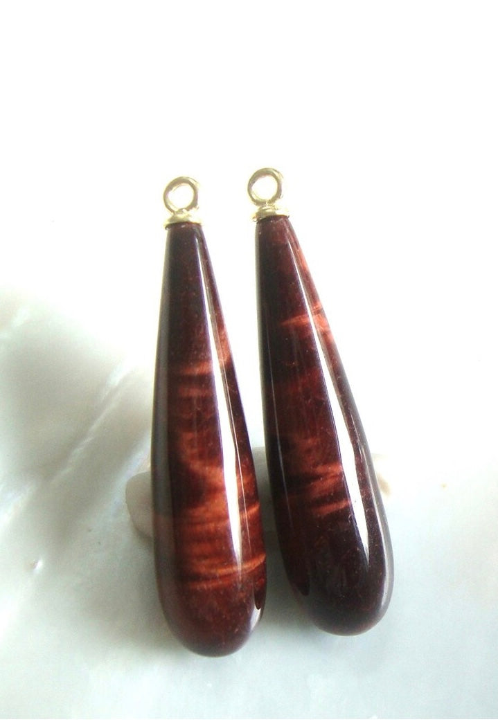 Two teardrop-shaped Tigers Eye Drops with gold clasps on a white background