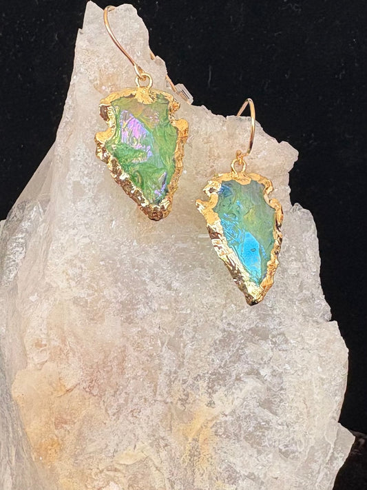 Jolie Esprit Titanium coated green quartz earrings with gold frames on a rock background