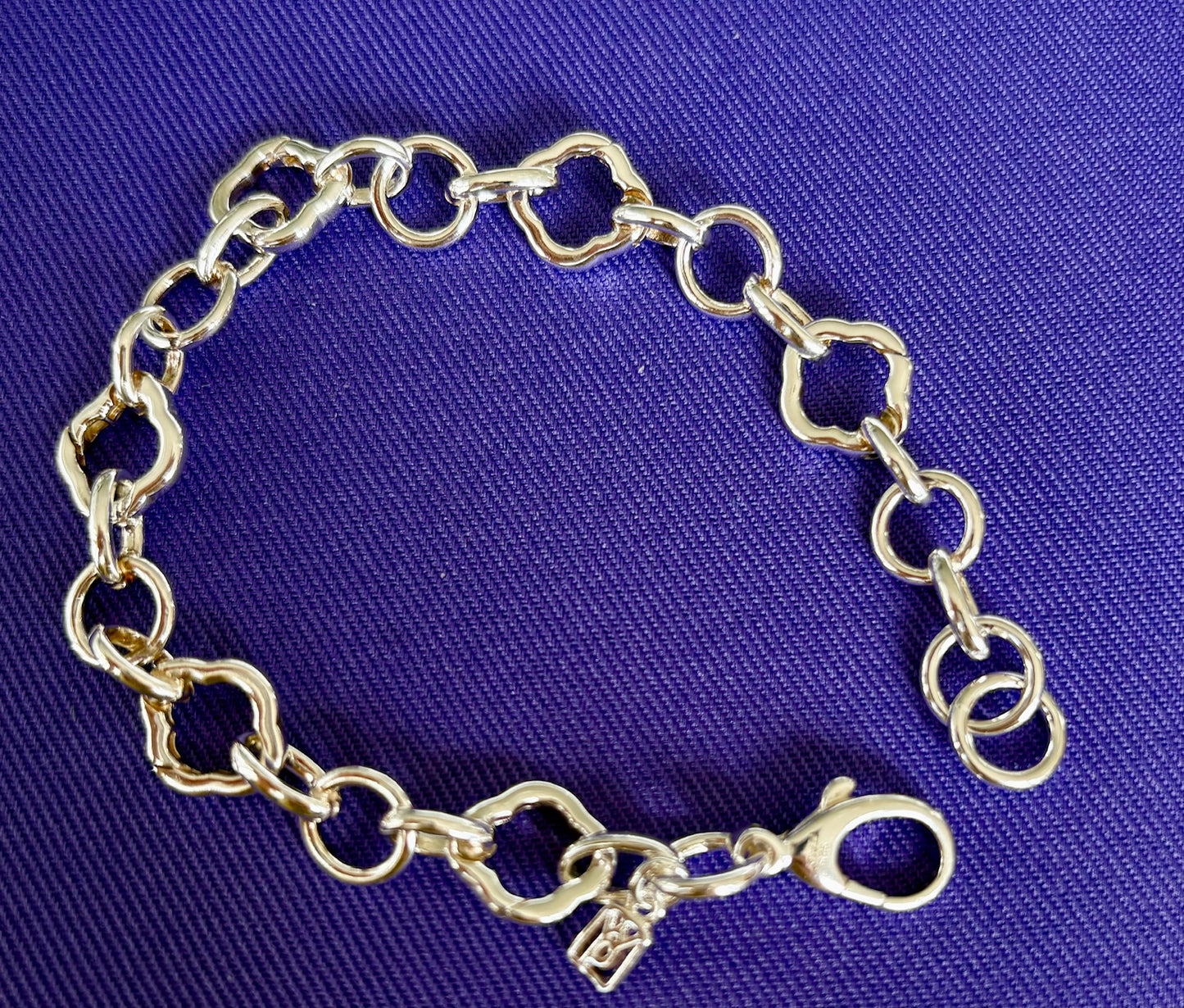 Waxing Poetic Sterling Silver charm bracelet on a blue fabric background