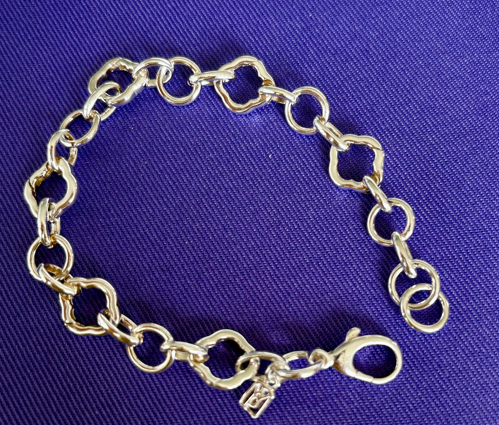 Waxing Poetic Sterling Silver charm bracelet on a blue fabric background