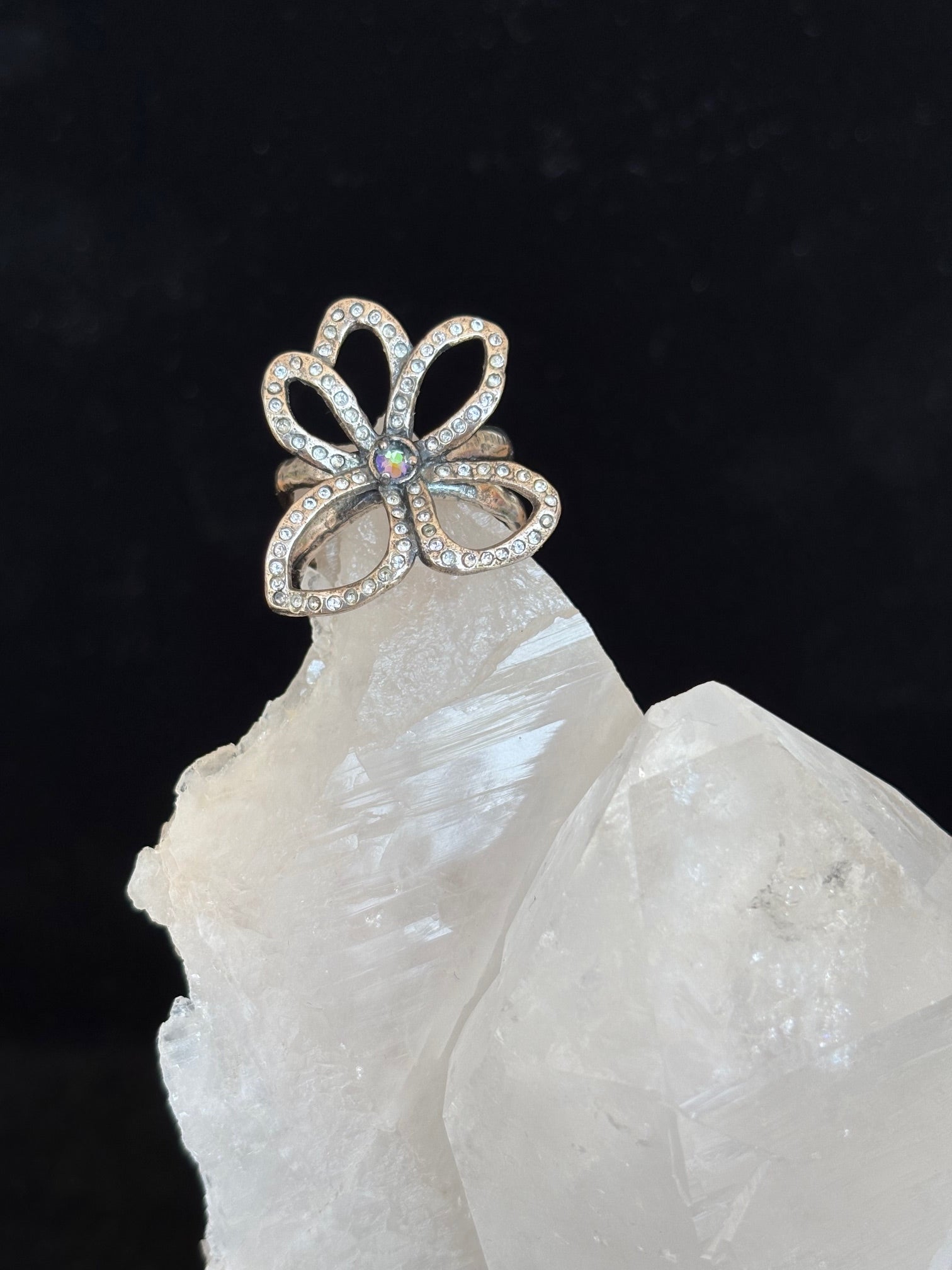 Flower-shaped silver ring with swarovski crystals on a dark background