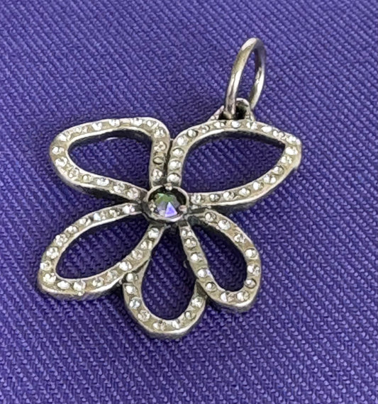 Sterling silver flower-shaped pendant on a purple fabric background. Waxing Poetic