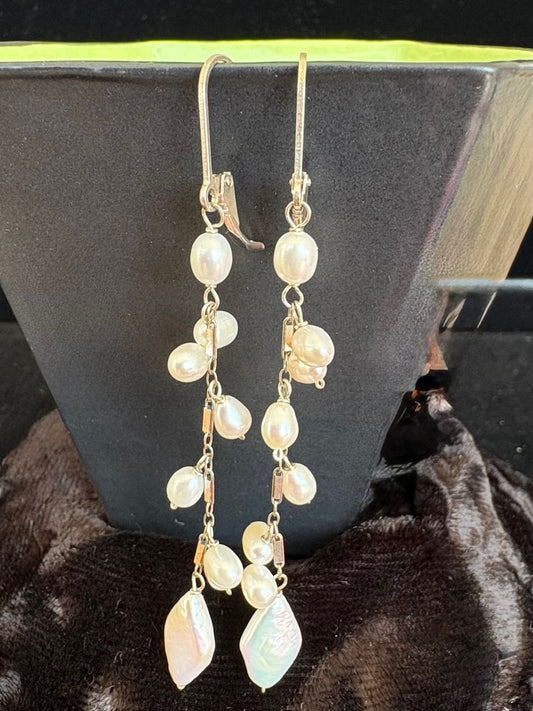 Pearl drop earrings on a dark surface