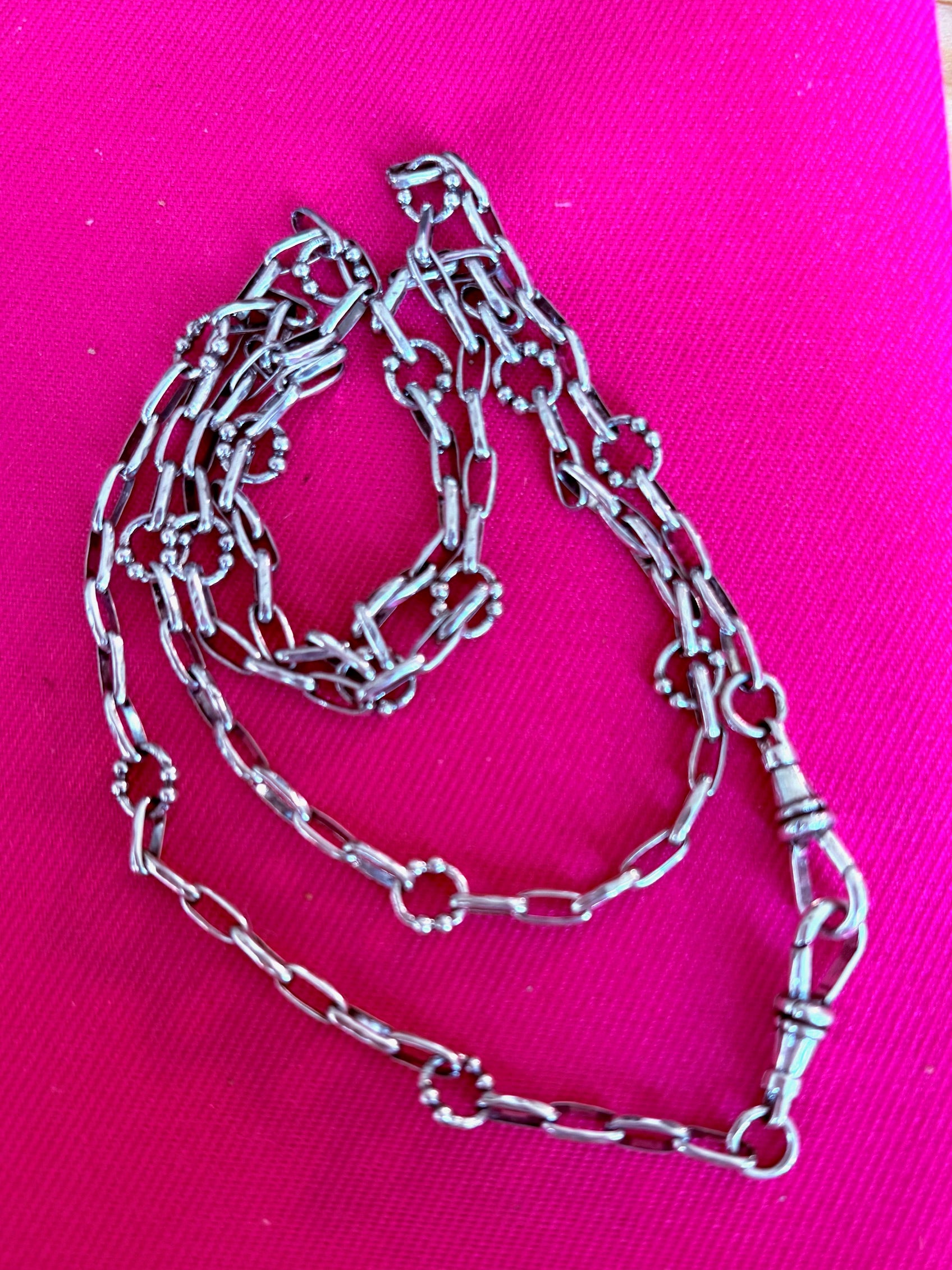 Waxing Poetic sterling silver chain on a pink background